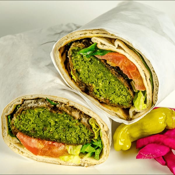 Two falafel wraps with lettuce and tomato, served with pickled peppers and turnips.