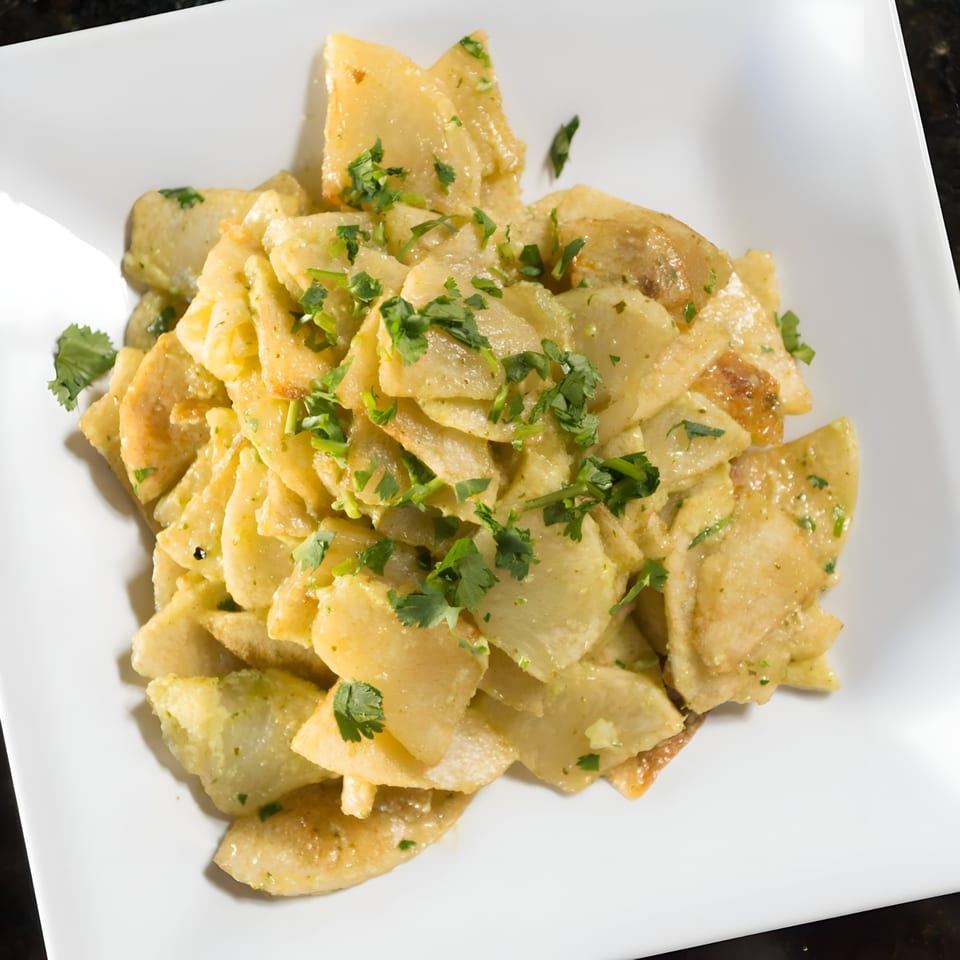 Mediterranean potato salad with herbs on a white square plate at The Green Olive Restaurant.